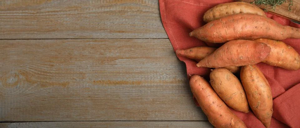 Fresh sweet potatoes on wooden table, top view with space for text. Banner de Stock Photos