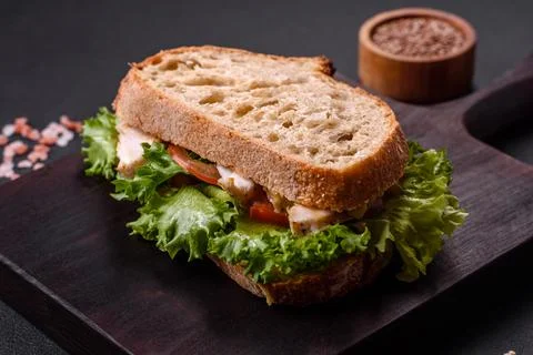 Fresh tasty sandwich with chicken, tomatoes and lettuce on a black plate Stock Photos