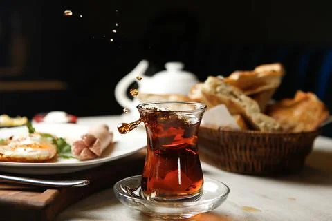 Fresh tea splashes in glass with bread and breakfast at table Stock Photos