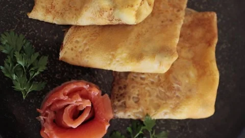 Fresh thin pancakes on a dark plate in the kitchen, dark background, shot on top Stock Footage 265066353