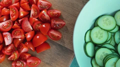 Fresh tomatoes and cucumbers are chopped and arranged on a wooden cutting board Stock-Footage 338290645