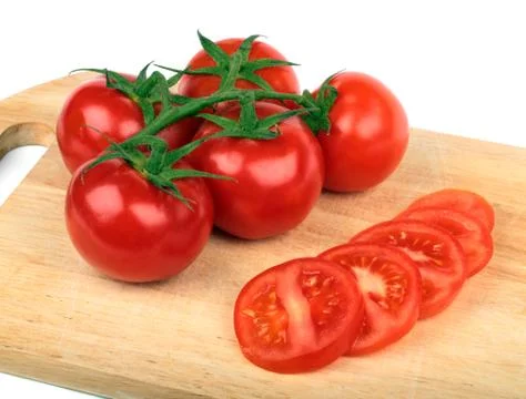 Fresh tomatoes and  tomatoes slices on a hardboard Stock Photos