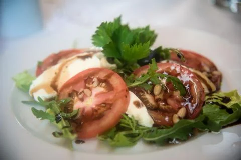 Fresh tomatoes with mozzarella, pine nuts and olives. Stock Photos