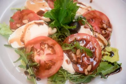 Fresh tomatoes with mozzarella, pine nuts and olives. Stock Photos
