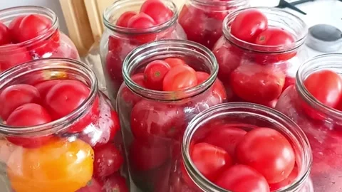 Fresh tomatoes packed in glass jars for homemade canning Stock Footage 345326575