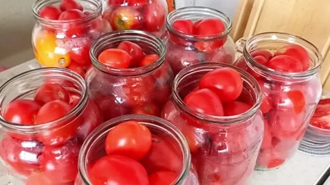 Fresh tomatoes packed in glass jars for homemade canning Stock Footage 345326588