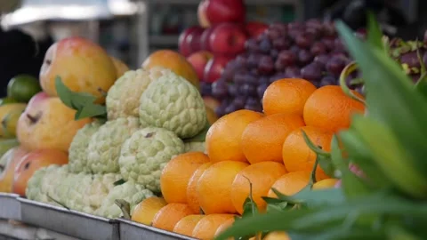Fresh tropical fruit piled high at a market stall with oranges and sugar apples Stock Footage 339279966