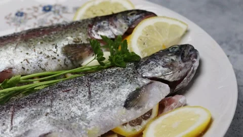 Fresh trout being prepared for baking, arranged on a white plate. Video stock 221406939