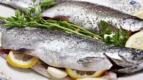 Fresh trout being prepared for baking, arranged on a white plate Stock-Footage 221406991