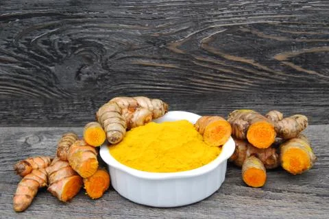Fresh Tumeric Root whole and cut with a dish of tumeric powder Stock Photos