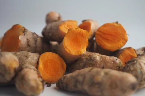 Fresh turmeric root displayed on a white surface Stock Photos