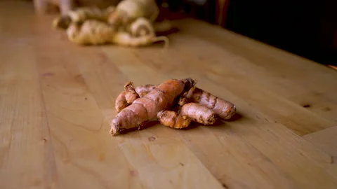 Fresh turmeric root on a wooden table with other vegetables in the background Stock Footage 145746420
