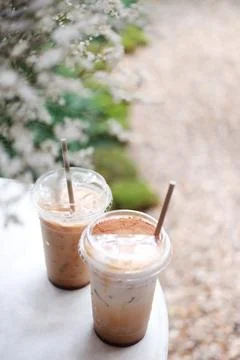 Fresh of two plastic glasses of ice latte coffee and dry grass flower in vase Stock Photos