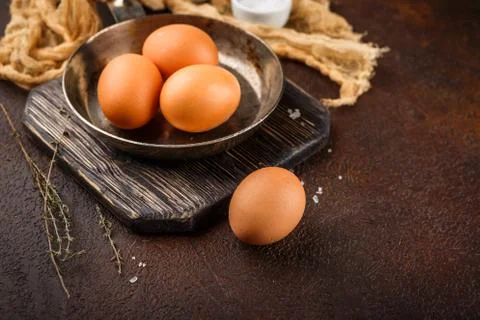 Fresh uncooked egg on a pan, stone or concrete background. Stock Photos