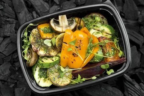 Fresh vegetable salad in black container on dark background Stock Photos