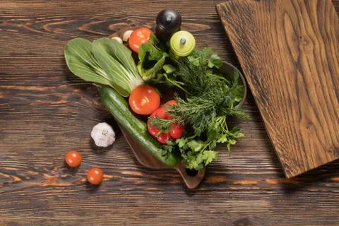 Fresh vegetables and fresh herbs lie on a wooden table Stock Photos