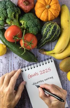 Fresh vegetables and fruit, two hands writing New Year's resolutions on a n.. Stock Photos