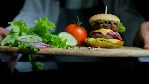 Fresh vegetables and tasty burger with cheese and beef cutlets. Chef on the Stock Footage 92503510