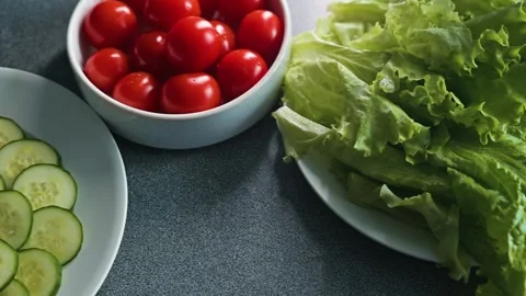 Fresh vegetables are displayed on a kitchen table, showcasing sliced cucumbers, Stock Footage 338290289