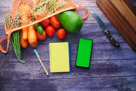 Fresh vegetables, cutting board, notepad and smart phone on table 写真素材