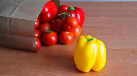 Fresh vegetables displayed on a kitchen table with a paper bag and various Stock Photos
