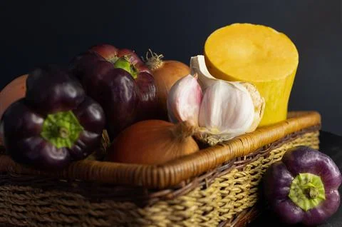 Fresh vegetables in a rustic basket with dark background. Stock Photos