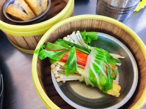 Fresh vegetables wrapped in cabbage served in a bamboo steamer at a local m.. Stock Photos