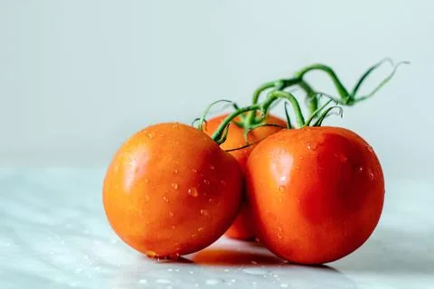 Fresh washed red tomatoes on green branch on kitchen table Stockfoto's