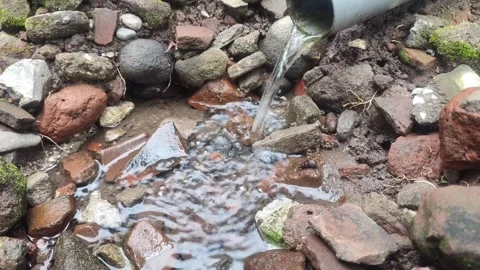 Fresh water flows gently over a pile of natural stones and red bricks Stock Footage 309789622