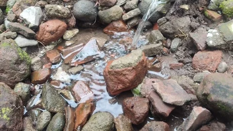 Fresh water flows gently over a pile of natural stones and red bricks Stock Footage 309789658