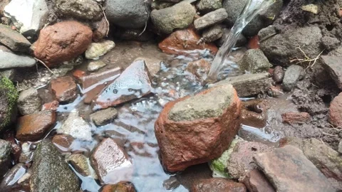 Fresh water flows gently over a pile of natural stones and red bricks Stock Footage 309789669