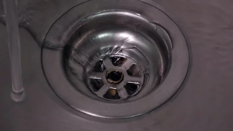 Fresh water running down plug hole in stainless steel sink. Close up, zoom in. Stock Footage 104782785
