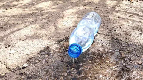 Fresh Water Spilling from Plastic Bottle onto Dry Ground Stock Footage 344558886