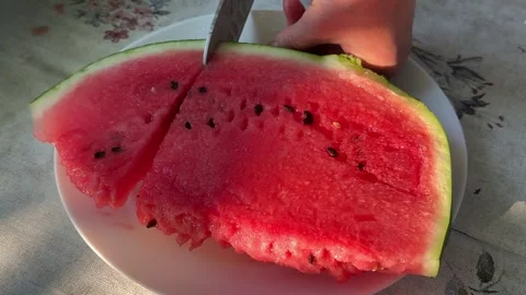 Fresh watermelon being sliced with a large kitchen knife on a rustic table Stock Footage 345179204