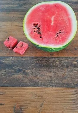 Fresh watermelon cut in half on rustic wooden table. Stock Photos