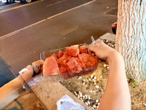 Fresh Watermelon Slices in a Plastic Container on a City Street at Night Stock Photos
