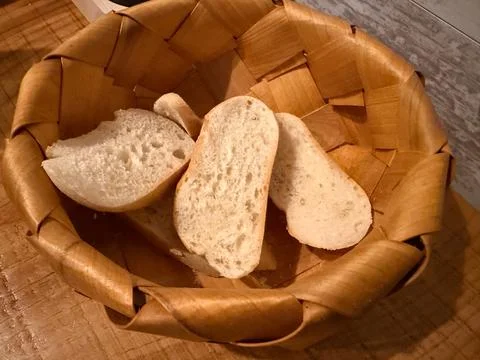 Fresh white bread slices in a rustic woven basket on a wooden surface for tex Stock Photos