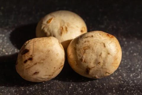 Fresh white button mushrooms on a dark stone surface with dramatic lighting Stock Photos