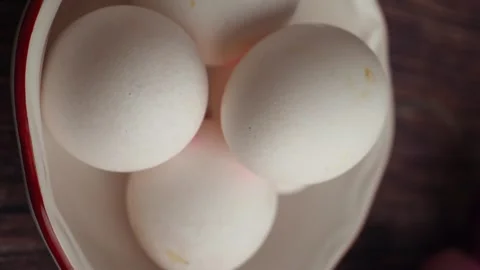 Fresh white chicken eggs in small ceramic heart bowl on dark wooden table c.. Video stock 331835947