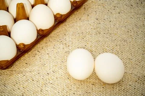 Fresh white eggs displayed on a textured surface with a carton Stock Photos