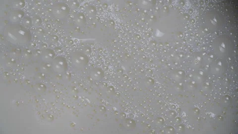 Fresh white milk with milk bubbles popping in the kitchen Stock Footage 333688202