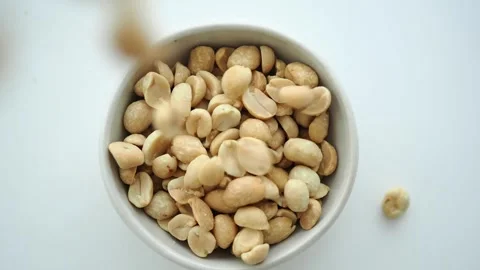 Fresh white peanuts drops in a small bowl on a white surface Stock Footage 339995394
