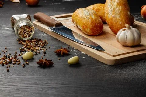 Fresh white wheat bread on a cutting board on a black wooden table Stock Photos