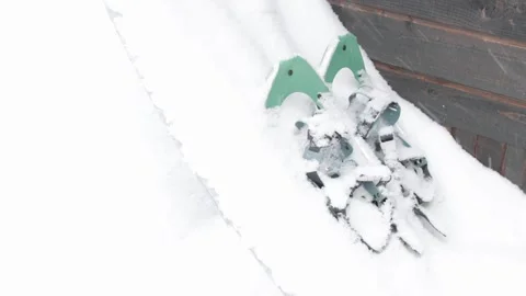 Fresh white winter snow falling on pair of green snowshoes Stock Footage 303256523