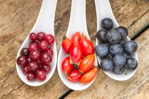 Fresh wild berries in ceramic spoons on wood background. Healthy food Стоковые фото