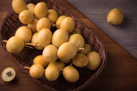 Fresh yellow dates on a sprig in wicker plate on rustic wooden background. Fl Stock Photos