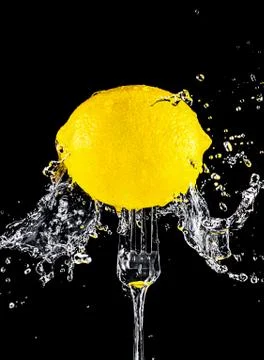 Fresh yellow lemon on a fork in splashes of water Stock Photos