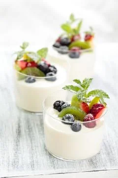 Fresh yogurt with berries. On white rustic table. Focus on  kiwi and blueberry i Stock Photos