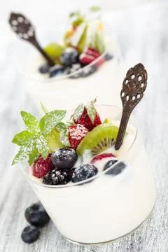Fresh yogurt with berries. On white rustic table Stock Photos
