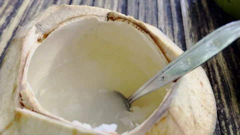 Fresh young coconut drink served inside opened shell with spoon 스톡 동영상 346742770